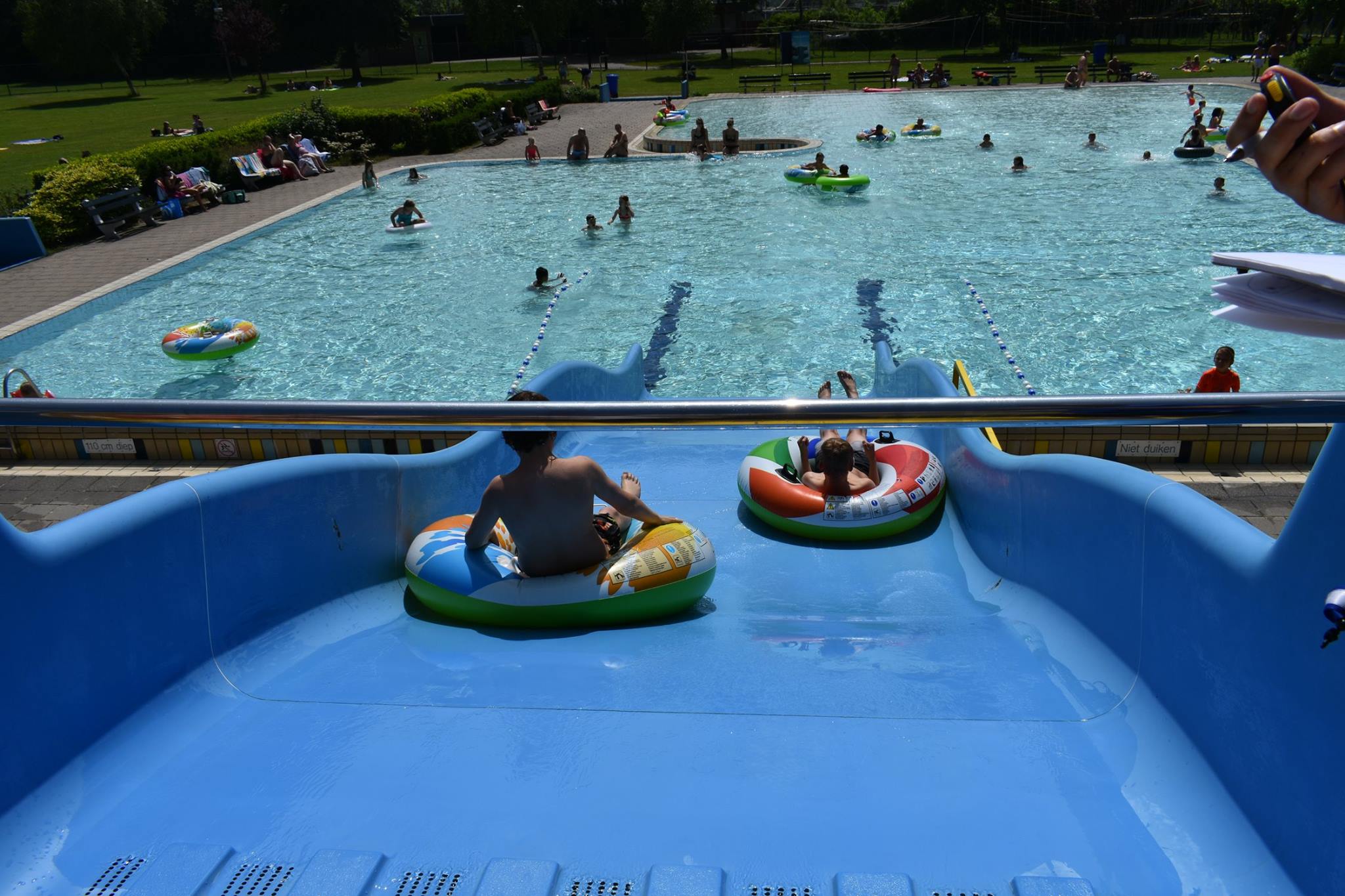 Twee kinderen in zwembanden van de glijbaan in Zwembad de Hoornse Vaart